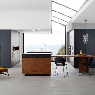 Exemple d'une très grand cuisine américaine tendance en L avec un placard à porte shaker, des portes de placard noires, béton au sol et un îlot central.