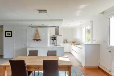 Medium sized contemporary galley open plan kitchen in Rennes with beaded cabinets, white cabinets, white splashback, integrated appliances, ceramic flooring, a breakfast bar, grey floors and white worktops.