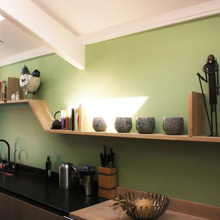 This is an example of a large contemporary galley separate kitchen in Bordeaux with an integrated sink, flat-panel cabinets, light wood cabinets, granite benchtops, black splashback, panelled appliances, concrete floors and no island.