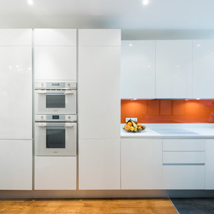 Design ideas for a mid-sized modern u-shaped open plan kitchen in Paris with an integrated sink, beaded inset cabinets, white cabinets, quartzite benchtops, orange splashback, glass tile splashback and panelled appliances.
