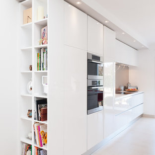 Idées déco pour une grand cuisine linéaire contemporaine avec des portes de placard blanches, une crédence grise, un placard à porte affleurante, un plan de travail en quartz, une crédence en dalle métallique et un électroménager encastrable.