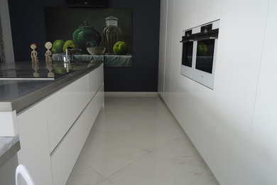 マルセイユにある高級な広いモダンスタイルのおしゃれなキッチン (一体型シンク、インセット扉のキャビネット、白いキャビネット、ステンレスカウンター、白い調理設備、大理石の床、白い床、グレーのキッチンカウンター) の写真