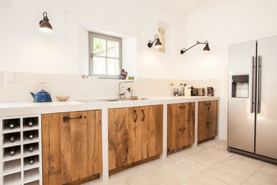Exemple d'une cuisine linéaire nature en bois clair avec un placard à porte affleurante, une crédence beige, un électroménager en acier inoxydable et un sol en carrelage de céramique.