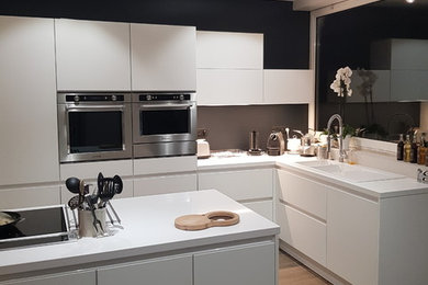 Offene, Große Küche in L-Form mit Küchenrückwand in Weiß, hellem Holzboden, Kücheninsel und braunem Boden in Lille