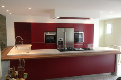 Photo of a large contemporary u-shaped kitchen/diner in Grenoble with a single-bowl sink, flat-panel cabinets, red cabinets, limestone worktops, stainless steel appliances, ceramic flooring and a breakfast bar.