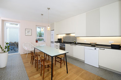 Example of a large trendy single-wall light wood floor open concept kitchen design in Angers with an undermount sink, white backsplash and no island