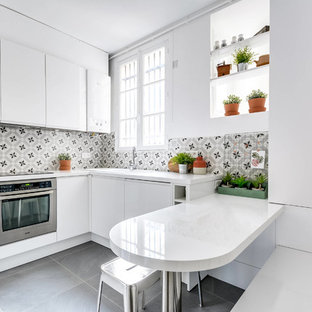 Idée de décoration pour une cuisine américaine design en L de taille moyenne avec un évier posé, un placard à porte plane, des portes de placard blanches, une crédence multicolore, une crédence en carreau de ciment, un électroménager en acier inoxydable, un sol gris, un plan de travail en stratifié, un sol en carrelage de céramique, un îlot central et un plan de travail blanc.