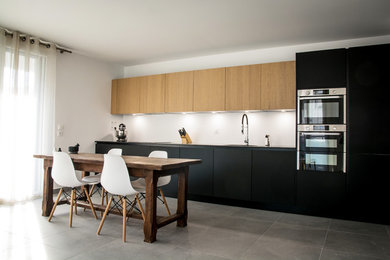 Medium sized contemporary single-wall open plan kitchen in Grenoble with a submerged sink, beaded cabinets, black cabinets, granite worktops, stainless steel appliances, ceramic flooring, no island, grey floors and black worktops.