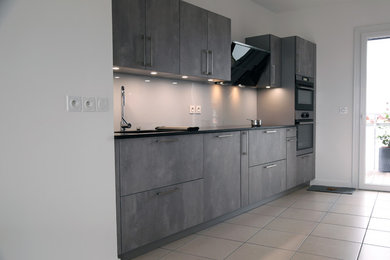 Imagen de cocina minimalista de tamaño medio abierta sin isla con encimera de granito, salpicadero blanco, electrodomésticos negros y encimeras negras