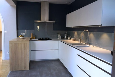 Cette photo montre une cuisine moderne en U avec un évier intégré, un placard à porte plane, des portes de placard blanches, un plan de travail en surface solide, une crédence grise et une crédence en carreau de verre.