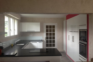 Cette photo montre une cuisine ouverte moderne de taille moyenne avec un évier 1 bac, des portes de placard blanches, un plan de travail en granite, une crédence en feuille de verre, un électroménager en acier inoxydable, un sol en carrelage de céramique et un sol gris.