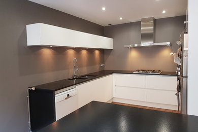 Cette image montre une grande cuisine minimaliste en L avec plan de travail noir.