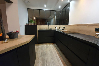 Inspiration for a mid-sized modern u-shaped light wood floor open concept kitchen remodel in Nantes with an undermount sink, flat-panel cabinets, black cabinets, laminate countertops, wood backsplash, black appliances, an island and black countertops