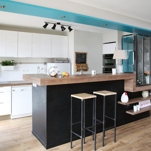 Aménagement d'une grand cuisine ouverte parallèle scandinave avec un placard à porte plane, des portes de placard blanches, une crédence blanche, un électroménager blanc, un sol en bois clair et une péninsule.