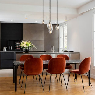 Exemple d'une grand cuisine ouverte moderne avec une façade en inox et un sol en bois clair.