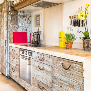 Aménagement d'une cuisine linéaire et beige et marron éclectique fermée et de taille moyenne avec des portes de placard en bois vieilli, une crédence beige, un évier posé, un placard à porte affleurante, un plan de travail en calcaire, une crédence en pierre calcaire, un électroménager en acier inoxydable, un sol en calcaire, un îlot central, un sol beige et un plan de travail beige.