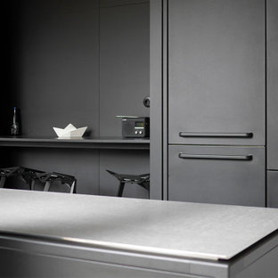 This is an example of a mid-sized contemporary l-shaped open plan kitchen in Lyon with an undermount sink, beaded inset cabinets, black cabinets, zinc benchtops, panelled appliances, concrete floors, with island, grey floor and grey benchtop.