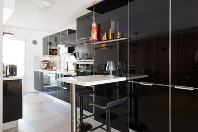 Idée de décoration pour une cuisine parallèle et encastrable design avec un évier encastré, des portes de placard noires, un plan de travail en quartz, une crédence blanche et un plan de travail blanc.