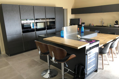 Design ideas for a large contemporary galley kitchen/diner in Lyon with a submerged sink, black cabinets, granite worktops, integrated appliances, ceramic flooring, an island, grey floors and black worktops.