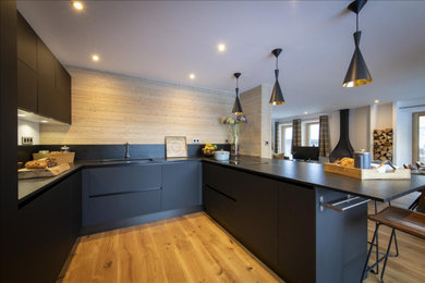 Aménagement d'une grande cuisine ouverte contemporaine en U avec des portes de placard noires, un plan de travail en granite et îlot.