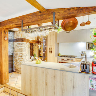 Cette photo montre une cuisine ouverte nature en U de taille moyenne avec un évier 2 bacs, un placard à porte plane, des portes de placard en bois clair, un plan de travail en surface solide, un sol en carreau de terre cuite, un sol marron, un plan de travail beige, un électroménager en acier inoxydable, une péninsule et un plafond en poutres apparentes.