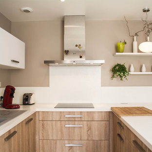 Inspiration pour une petit cuisine américaine minimaliste en U avec un évier 1 bac, une crédence blanche, un électroménager en acier inoxydable, une péninsule et des portes de placard en bois clair.