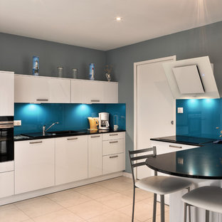Inspiration pour une cuisine ouverte design en U de taille moyenne avec un évier 1 bac, un plan de travail en quartz, une crédence noire, une crédence en carreau de verre, un électroménager encastrable, un sol en carrelage de céramique, un sol blanc et un plan de travail noir.