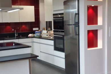 Photo of a large contemporary l-shaped open plan kitchen in Paris with a submerged sink, beige cabinets, granite worktops, red splashback, integrated appliances, ceramic flooring and an island.