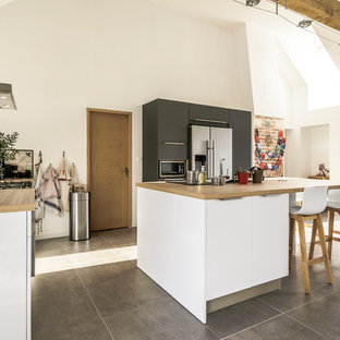 Cette photo montre une cuisine américaine scandinave en L de taille moyenne avec des portes de placard blanches, un plan de travail en stratifié, une crédence en carreau de ciment, un électroménager en acier inoxydable et un îlot central.