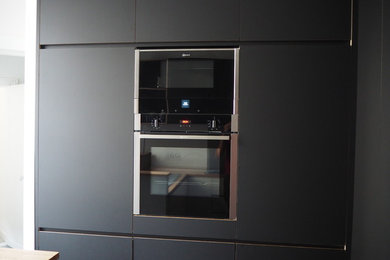 Inspiration pour une cuisine design en U avec des portes de placard noires et un plan de travail en bois.