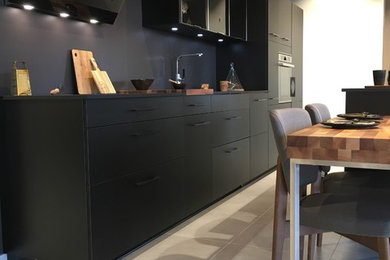 Inspiration for a large contemporary single-wall open plan kitchen in Grenoble with a single-bowl sink, beaded cabinets, stainless steel cabinets, soapstone worktops, black splashback, slate splashback, stainless steel appliances, cement flooring, an island and beige floors.