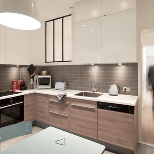 Idée de décoration pour une cuisine américaine design en L de taille moyenne avec un évier 1 bac, des portes de placard en bois clair, une crédence grise, un électroménager encastrable, un sol en carrelage de céramique et aucun îlot.