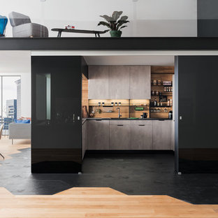 Idée de décoration pour une cuisine minimaliste en U avec un évier posé, un placard à porte plane, des portes de placard grises, une crédence beige, une crédence en bois, une péninsule, un sol noir et un plan de travail noir.