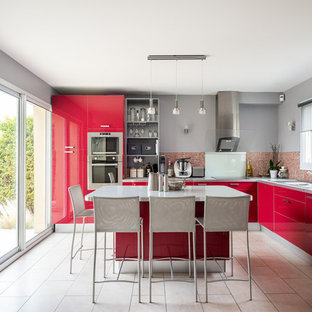 Inspiration pour une grand cuisine design en L avec un évier 2 bacs, un placard à porte plane, des portes de placard rouges, un plan de travail en stratifié, une crédence rouge, une crédence en mosaïque, un électroménager en acier inoxydable, un îlot central, un sol beige et un plan de travail gris.