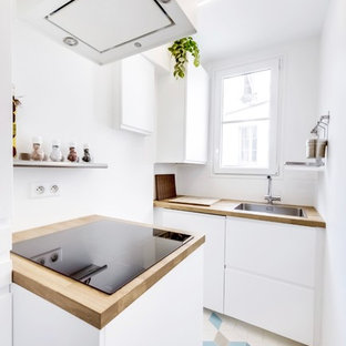 Cette image montre une cuisine ouverte parallèle nordique de taille moyenne avec un évier 1 bac, un placard à porte affleurante, des portes de placard blanches, un plan de travail en bois, une crédence blanche, une crédence en fenêtre, un électroménager en acier inoxydable, un sol en carrelage de céramique et aucun îlot.