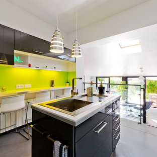 Idées déco pour une cuisine américaine parallèle contemporaine de taille moyenne avec un évier 1 bac, un placard à porte affleurante, des portes de placard grises, un plan de travail en stratifié, une crédence verte, un électroménager en acier inoxydable, béton au sol et un îlot central.