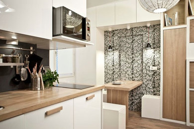 Esempio di una cucina minimal di medie dimensioni con ante bianche, paraspruzzi nero, pavimento in legno massello medio e nessuna isola