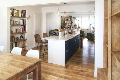Idéer för ett mellanstort eklektiskt vit kök, med en undermonterad diskho, släta luckor, blå skåp, mellanmörkt trägolv och en köksö