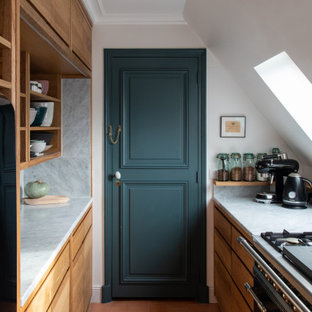 Réalisation d'une petit cuisine parallèle design fermée avec un placard à porte plane, des portes de placard en bois brun, une crédence grise, un électroménager noir, un sol en carreau de terre cuite, aucun îlot, un sol orange et un plan de travail gris.