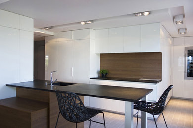 Cette photo montre une cuisine ouverte parallèle moderne de taille moyenne avec des portes de placard blanches et une péninsule.