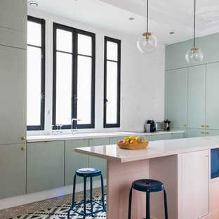 Idée de décoration pour une cuisine design en U avec un placard à porte plane, des portes de placards vertess, une crédence blanche, une péninsule, une crédence en dalle de pierre, un électroménager encastrable et un sol multicolore.