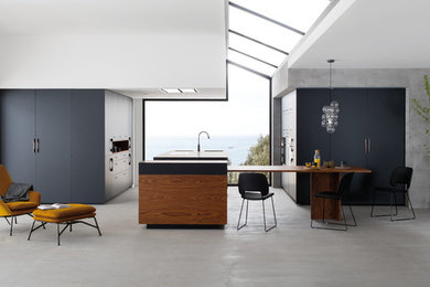 Inspiration for a large contemporary open plan kitchen in Grenoble with an integrated sink, beaded cabinets, black cabinets, wood worktops, stainless steel appliances, concrete flooring and an island.