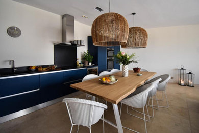 Пример оригинального дизайна: прямая кухня-гостиная в современном стиле с синими фасадами, черным фартуком, техникой из нержавеющей стали, бежевым полом и черной столешницей без острова