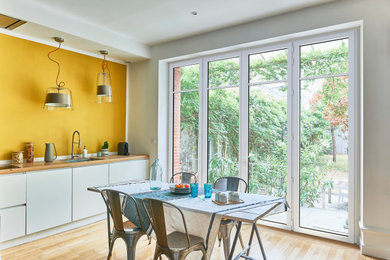 パリにある広いトラディショナルスタイルのおしゃれな独立型キッチン (アンダーカウンターシンク、インセット扉のキャビネット、白いキャビネット、木材カウンター、淡色無垢フローリング、アイランドなし) の写真