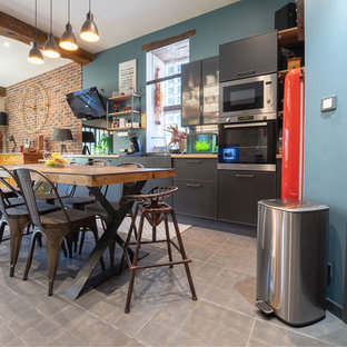 Inspiration pour une cuisine ouverte linéaire urbaine avec un évier de ferme, un placard à porte plane, des portes de placard noires, un plan de travail en bois, un électroménager en acier inoxydable, aucun îlot, un sol gris et un plan de travail marron.