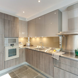 Inspiration pour une grand cuisine américaine design en L avec une crédence en feuille de verre, un électroménager en acier inoxydable, un sol en carrelage de céramique, aucun îlot, un évier intégré, un placard à porte plane, des portes de placard grises, un plan de travail en inox, une crédence grise, un sol gris et un plan de travail gris.