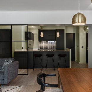 This is an example of a small contemporary u-shaped eat-in kitchen in Paris with an integrated sink, flat-panel cabinets, black cabinets, quartzite benchtops, white splashback, cement tile splashback, panelled appliances and a peninsula.