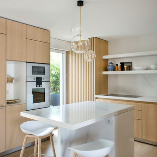 Réalisation d'une cuisine américaine design en L avec un placard à porte plane, des portes de placard beiges, un plan de travail en marbre, une crédence blanche, une crédence en marbre, un sol en bois brun, un îlot central, un sol beige et un plan de travail blanc.