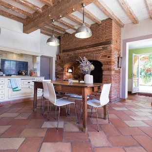 Idées déco pour une grand cuisine ouverte linéaire campagne avec un placard à porte plane, des portes de placard blanches, une crédence beige, un sol en carreau de terre cuite et un îlot central.