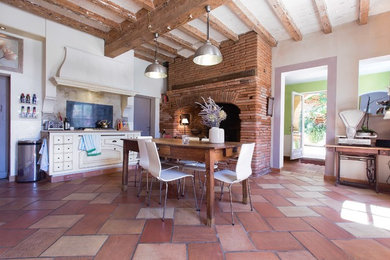 На фото: большая прямая кухня-гостиная в стиле кантри с плоскими фасадами, белыми фасадами, бежевым фартуком, полом из терракотовой плитки и островом